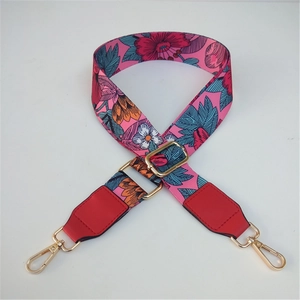 Close-up of adjustable pink floral bag strap with gold hooks and red leather ends