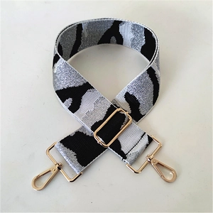 Close-up of camouflage woven shoulder strap with star patterns and gold metal buckles