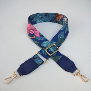 Macro detail of floral embroidered wide strap with golden swivel hooks and adjusters