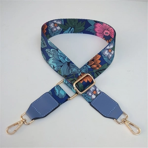 Detail of floral ethnic strap with golden metal hooks and light blue leather trim