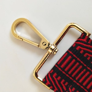 Detail of red and black jacquard strap with polished gold metal lobster clasp for bags
