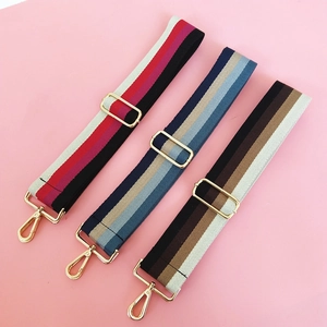 Close-up of thick striped cotton bag straps with adjustable gold-tone metal hardware