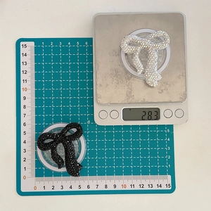 Detailed view of colorful rhinestone bow phone sockets weighing 28.3 grams on a digital scale