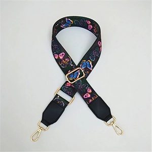 Close-up of wide adjustable bag strap with colorful butterfly patterns and gold hardware