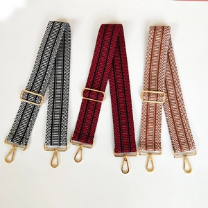 Close-up of three colorful adjustable wide fabric straps with gold metal swivel hooks
