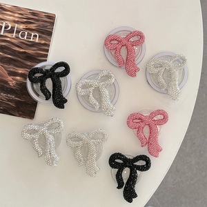 Set of 8 sparkling rhinestone bow phone grips in black pink and silver on white surface