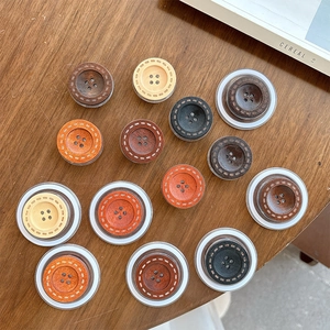 Detail of multi-color wooden button phone grips with 4-hole design on a warm wood surface