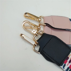 Close-up of light gold lobster clasps and leather joints on woven wide shoulder straps
