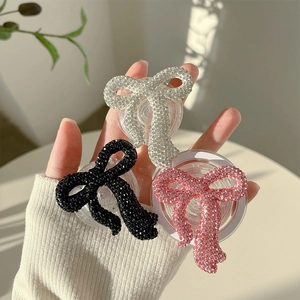 Sparkling rhinestone bow phone grip sockets in silver, black and pink on a transparent base