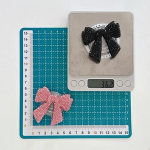 Macro view of crystal rhinestone bow phone grip on a scale showing size and 36g weight