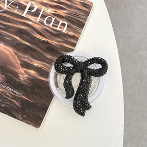 Macro shot of black rhinestone bow phone grip holder on a minimalist magazine background