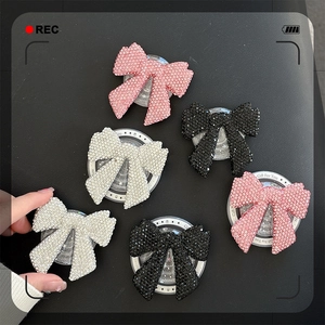 Close-up of sparkling rhinestone bow phone grips in pink, black and white colors