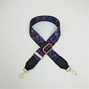 Close-up of adjustable woven shoulder strap with colorful feather patterns and gold hooks