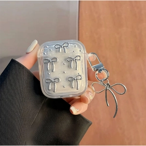 Close-up of clear AirPods case with silver glitter bows and ribbon keychain pendant