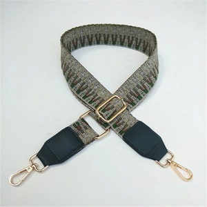 Detail of adjustable woven bag strap with geometric patterns and gold metal hooks
