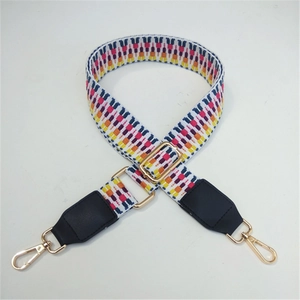 Close-up of geometric woven shoulder strap with gold metal buckle and leather ends