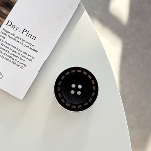 Top view of a black button-shaped magnetic phone grip with vintage industrial details