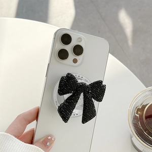 Detail of a black sequin bow phone grip with for you print on a white smartphone