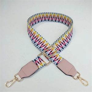 Detail of colorful geometric woven bag strap with pink leather ends and gold metal buckle
