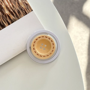 Detail of creative button-shaped phone grip with warm yellow finish and clear edges