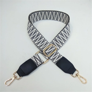 Close-up of black and white woven geometric pattern strap with gold metal buckle