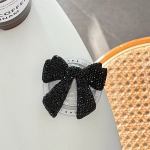 Detail of a sparkling black rhinestone bow phone grip on a clear acrylic base with Gift text