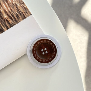 Detailed view of a brown wooden button-style phone socket grip on a white desk