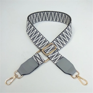 Close-up of black and white geometric woven strap with gold lobster clasps and grey leather