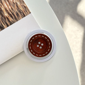 Macro detail of round wooden button phone grip with vintage brown grain and stitch texture