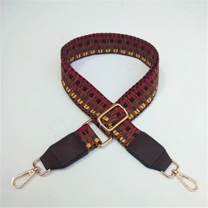 Close-up of ethnic patterned bag strap with gold metal buckle and brown leather ends