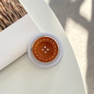Detail of wooden button phone grip with realistic grain on a minimalist white desk