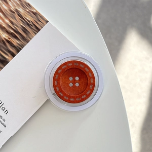 Detailed close-up of a wooden button-style phone grip and magsafe stand on a desk