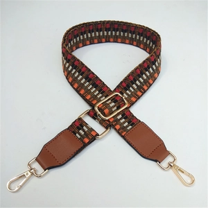 Detail of adjustable geometric woven shoulder strap with gold metal hooks and leather ends