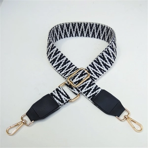 Detail of adjustable woven shoulder strap with black white pattern and gold metal hooks