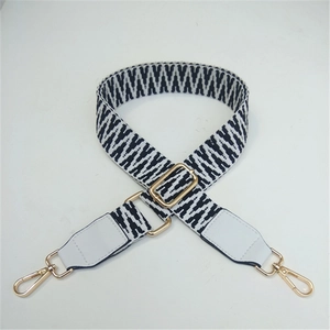 Detail of adjustable black and white woven strap with golden hooks and PU leather ends