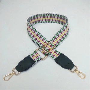 Detail of adjustable woven bag strap with geometric patterns and gold lobster clasps