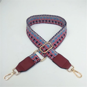 Detail of adjustable woven shoulder strap with ethnic geometric patterns and gold hardware