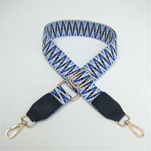 Close-up of adjustable woven strap with blue wavy patterns and gold metal hooks