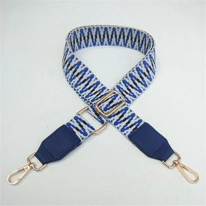 Detail of adjustable woven bag strap with blue geometric pattern and gold swivel hooks