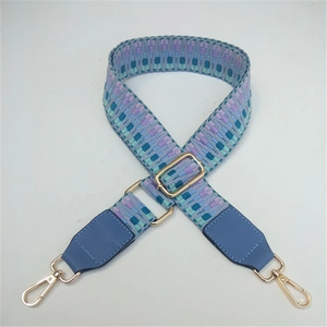 Detail of adjustable geometric woven shoulder strap with blue leather and gold hardware