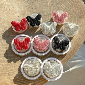 Sparkling rhinestone butterfly phone grips in multiple colors on a natural wooden tray