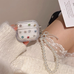 Detailed view of clear AirPods case with colorful star crystals and pearl lanyard strap