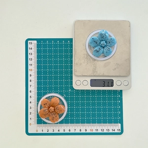 Flower phone grip detail showing 31g weight on scale and 5cm size on measuring mat