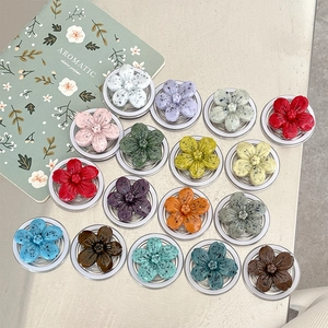 Detailed view of colorful flower phone grips in 17 matte colors on a light desk