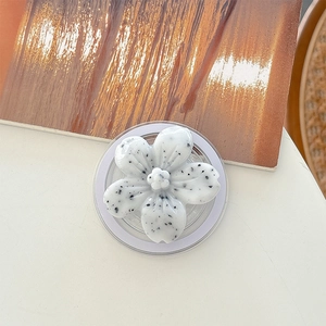 Detailed top view of a white flower phone grip with black spots on a marble finish