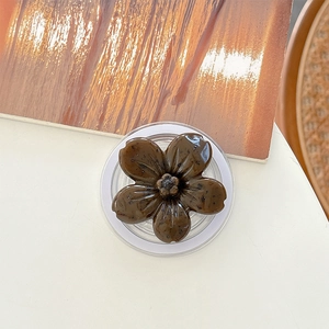 Macro view of dark brown floral phone grip with glossy vintage texture on white desk