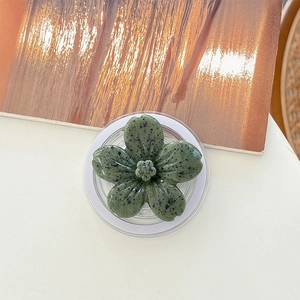 Macro shot of dark green flower phone grip with artistic ink splatter texture and clear base