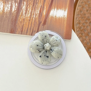 Close-up of matte marble textured floral phone grip with adjustable stand on white surface