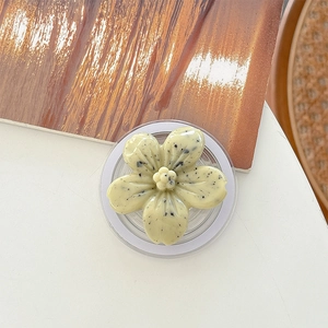 Detail view of flower-shaped phone grip with marble spots on a white and wood surface