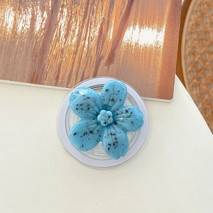 Close-up of light blue flower phone grip with black speckled pattern and clear base